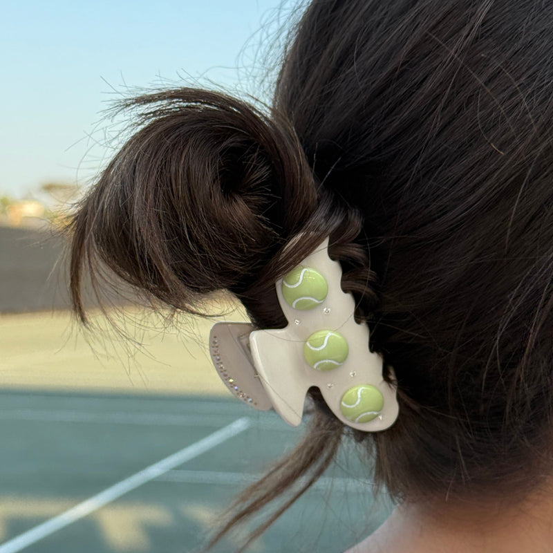 Person with a hair tie featuring green beads on a tennis court